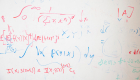 A dry-erase board with red and blue equations written all over it 