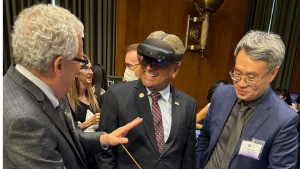Jeffrey krolik, on left, and Yiran Chen, on right, demonstrate an AR system to a smiling government official (center) 