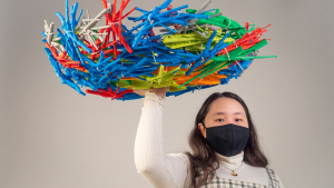 student holding colorful 3-D printed hawk's nest