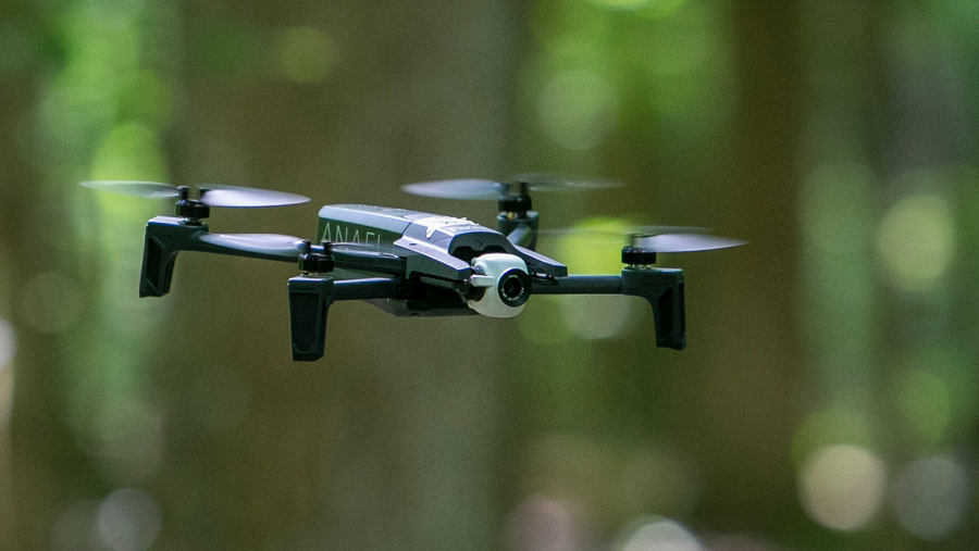 a drone in focus flying in a forest not in focus
