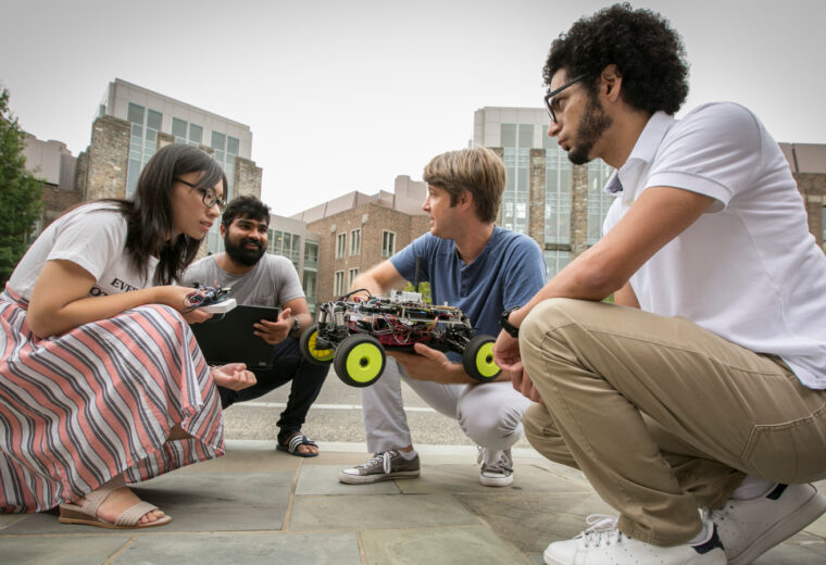 faculty member and graduate students work on a project outside