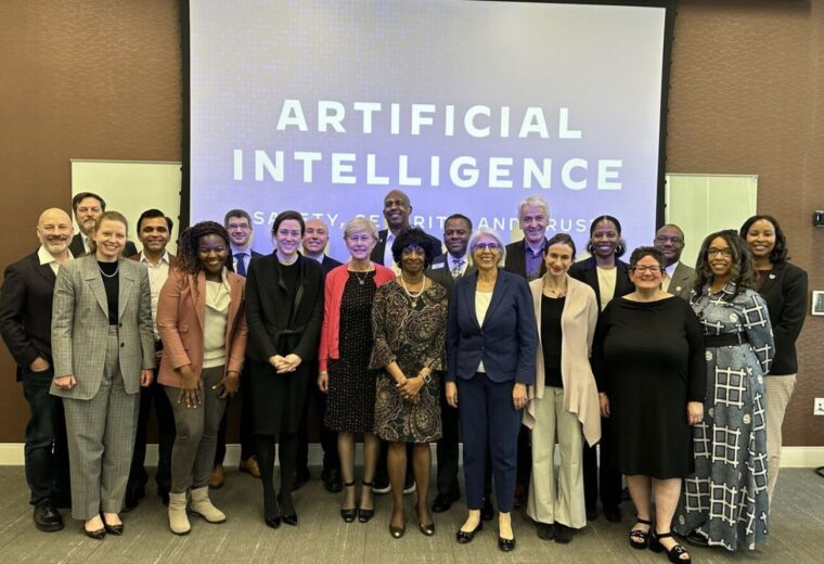 A group of people standing in front of a screen that says Artificial Intelligence