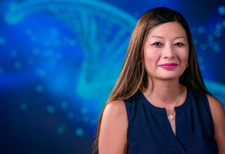 A woman in front of a blue background of helical DNA