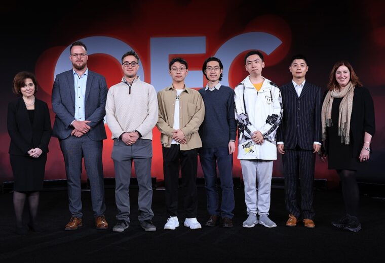 Eight people standing in a row holding an award in front of an OEC red banner