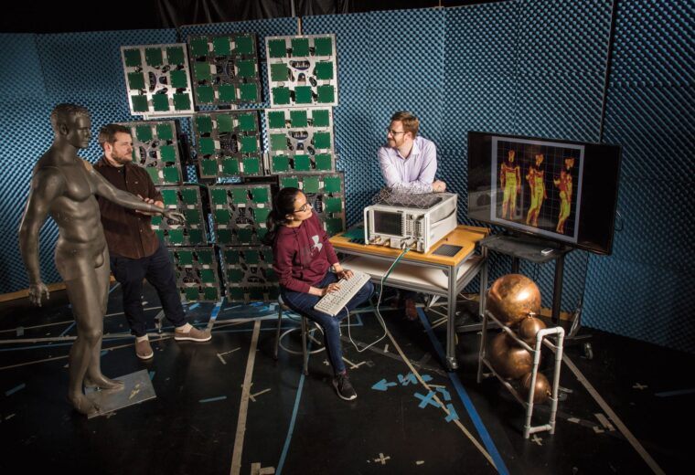 three people in a lab with a mannikin and security sensing equipment