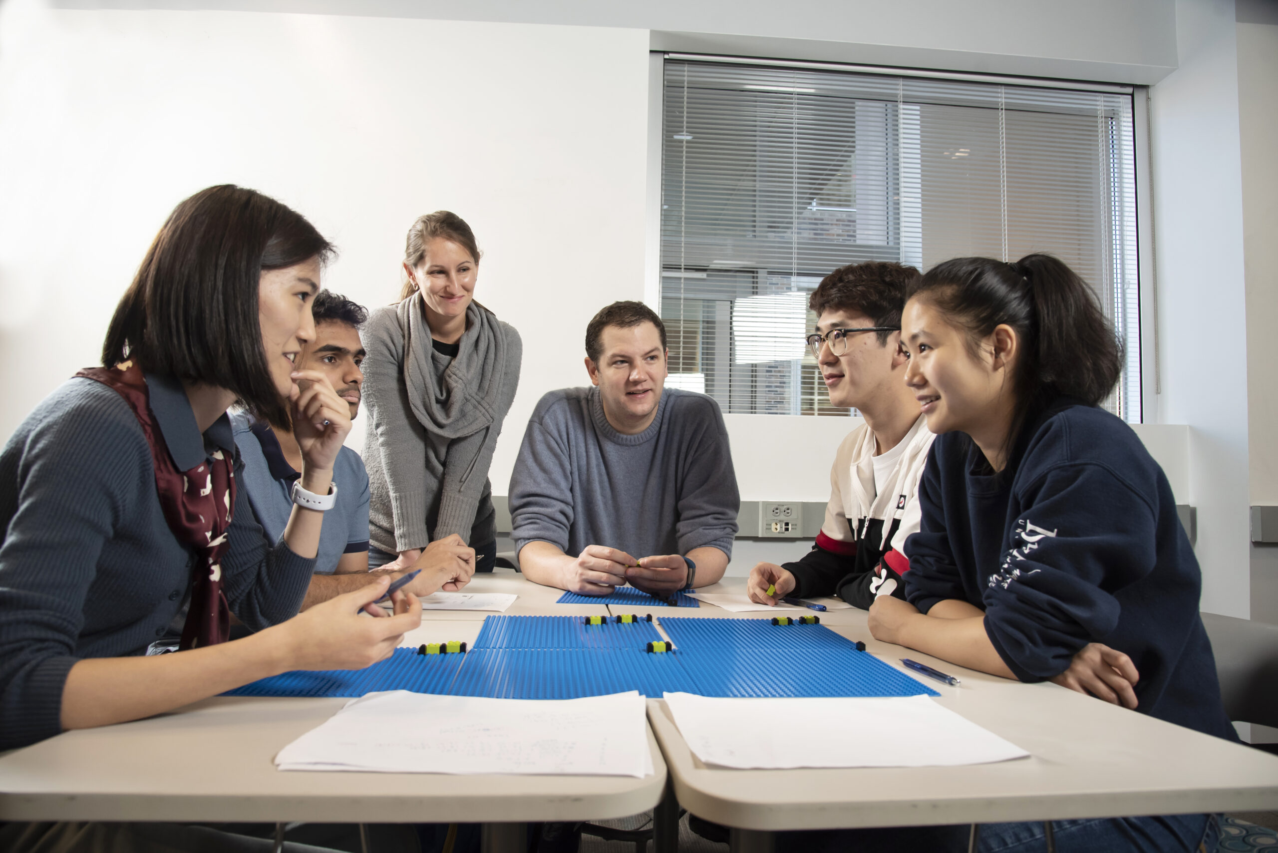 professor leads a group of graduate students through a coding exercise using Lego bricks