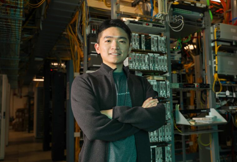 Tingjun Chen, who will study analog radio-over-fiber technology, stands in a telecommunications building.