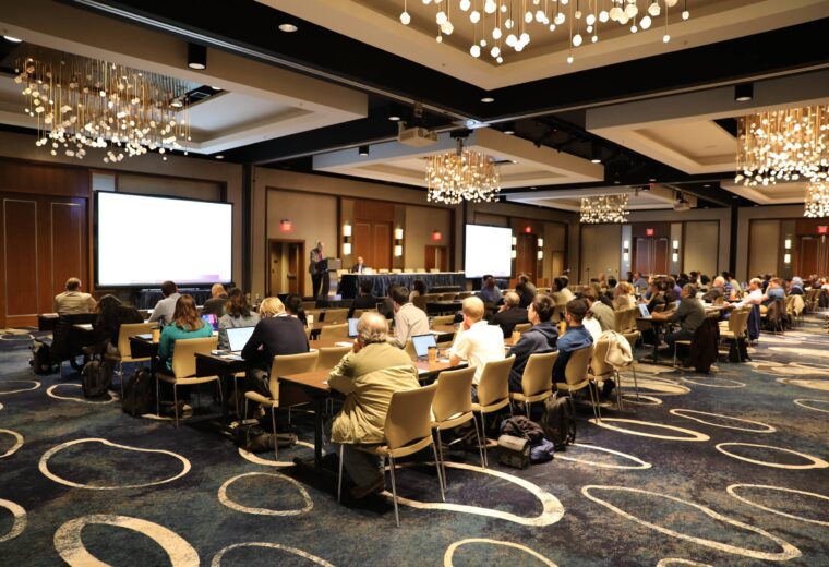 a large room of people and two large screens