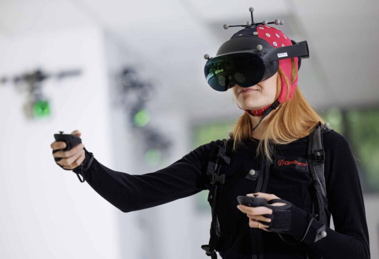a woman in a black jump suit and a red hood wearing a VR headset